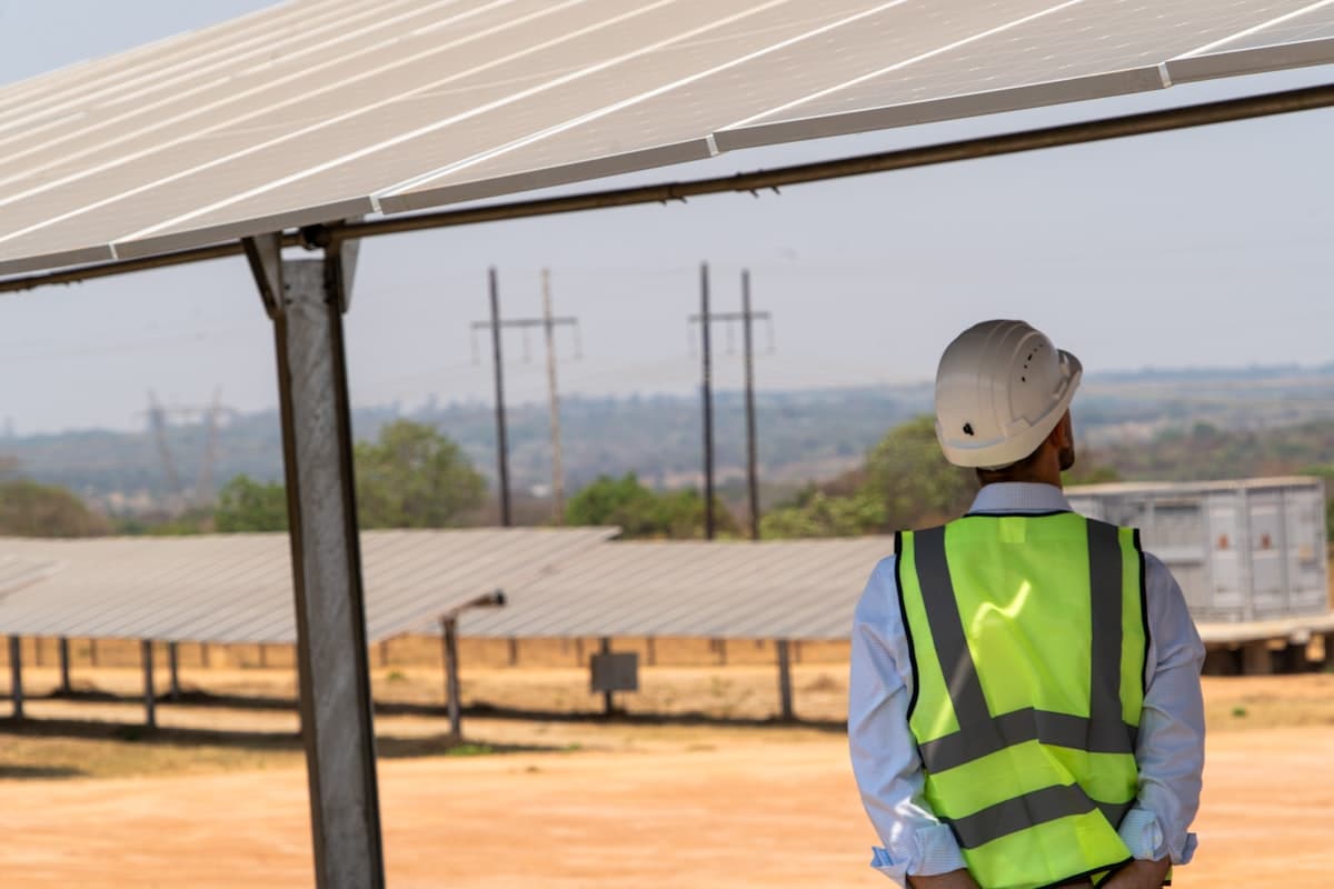 Technicien en gilet de sécurité sous une structure photovoltaïque au sol